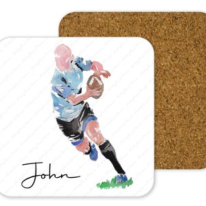 May include: A watercolor illustration of a rugby player running with the ball. The player is wearing a blue and white jersey and black shorts. The player's name, "John", is written in cursive at the bottom of the image.