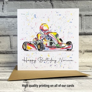 May include: A colorful birthday card featuring a watercolor illustration of a person driving a go-kart. The card has a white background with colorful splatters and the text "Happy Birthday Noruwa".