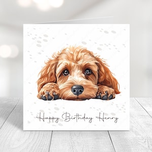 Peut inclure: Une carte d'anniversaire avec une illustration mignonne d'un chien brun et blanc avec le texte "Happy Birthday Henry" sur un fond blanc avec des empreintes de pattes.