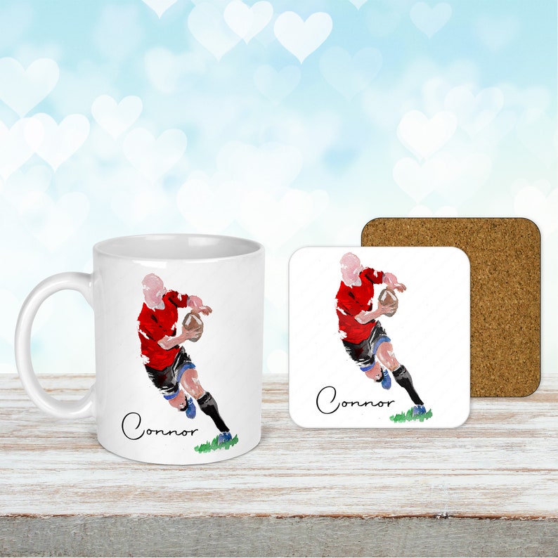 May include: White ceramic mug and square coaster set featuring a watercolor illustration of a rugby player in a red jersey. The name "Connor" is written in cursive. The coaster has a cork backing.