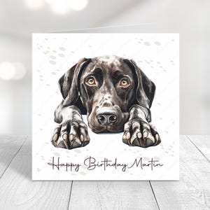 Peut inclure: Une carte d'anniversaire avec un chien Braque Allemand à poil court noir et blanc aux yeux bruns. Le chien est couché, ses pattes au premier plan. La carte porte l'inscription "Happy Birthday Martin".