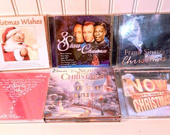 May include: A collection of Christmas music CDs. The CDs feature various artists and titles, including "Christmas Wishes," "3 Stars of Christmas," and "Frank Sinatra Christmas." The album covers display festive imagery, such as Santa Claus and winter scenes.