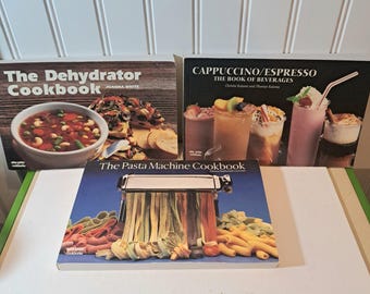 May include: Three cookbooks are displayed, featuring titles like "The Dehydrator Cookbook," "Cappuccino/Espresso: The Book of Beverages," and "The Pasta Machine Cookbook." The covers showcase images of food and beverages, including soups, pasta, and coffee drinks.