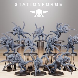 Könnte beinhalten: Eine Sammlung von neun grauen, unbemalten Miniatur-Alien-Kreaturen, die jeweils mit scharfen Krallen, segmentierten Panzern und gezahnten Kiefern ausgestattet sind. Der Text STATIONFORGE und ein Totenkopf-Logo sind oben im Bild zu sehen.