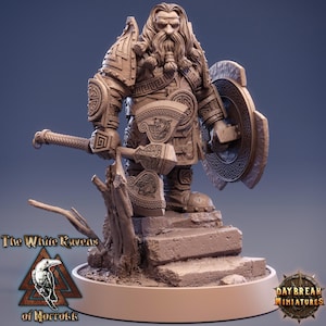 May include: A detailed figurine of a dwarf warrior, holding a hammer and shield. The figure is clad in armor with intricate carvings and stands on a stone base. The base has the text "The White Ravens of Norrok" and "Daybreak Miniatures".