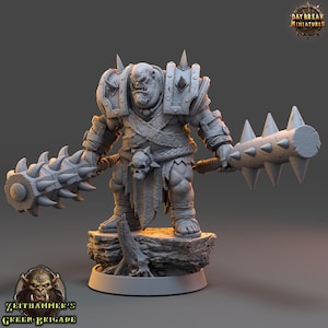 May include: A detailed, gray miniature figure of a muscular orc warrior, holding two spiked clubs. The orc is clad in armor with shoulder spikes and a skull-adorned loincloth. The figure stands on a rocky base, with the text "Daybreak Miniatures" and "Zeithammer's Green Brigade".