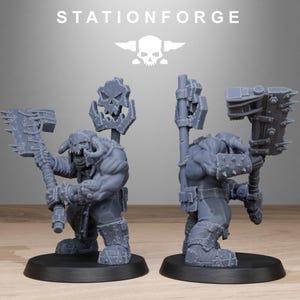 May include: Two gray miniature figures of a fantasy warrior with horned helmets, wielding large axes and skull-topped staffs. The figures are on black bases. The word "STATIONFORGE" is printed above the figures, along with a skull logo.