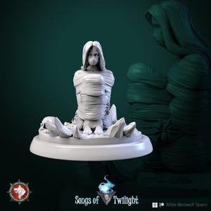 May include: A white figurine of a person wrapped in bandages, seated on a round base with jagged rock formations and a skull. The figure has long hair and a serene expression. The base has the text "Songs of Twilight" and "White Werewolf Tavern".