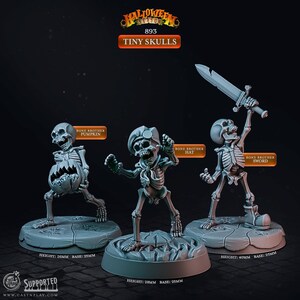 Könnte beinhalten: Drei graue Miniatur-Skelettfiguren mit der Aufschrift Tiny Skulls. Eine hält einen Kürbis, eine trägt einen Hut und eine hält ein Schwert. Jede steht auf einem runden Sockel mit einer Höhe von 26mm, 28mm beziehungsweise 40mm.