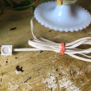 May include: White milk glass lamp base with a beaded edge and a white cord with a two-prong plug.