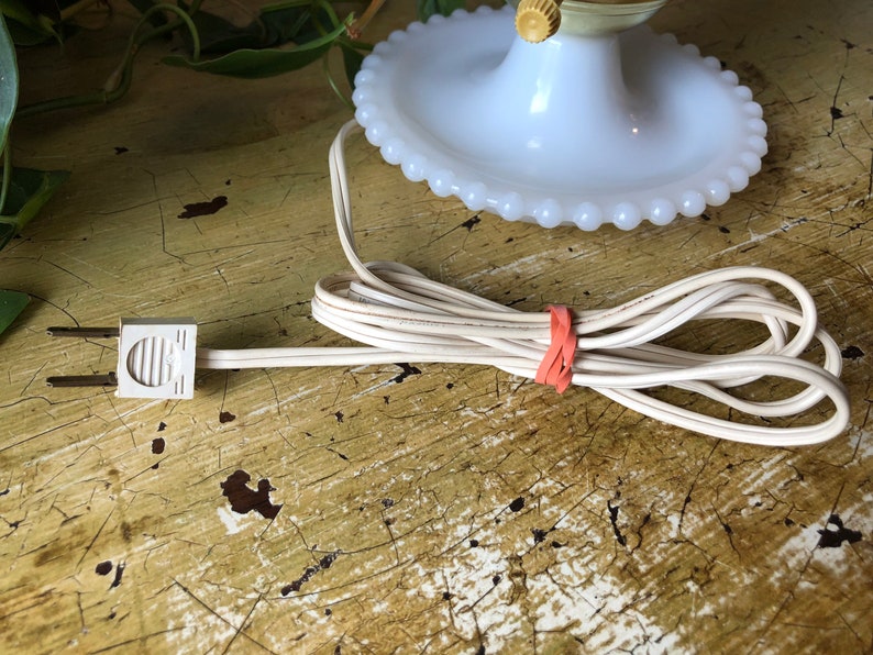May include: White milk glass lamp base with a beaded edge and a white cord with a two-prong plug.