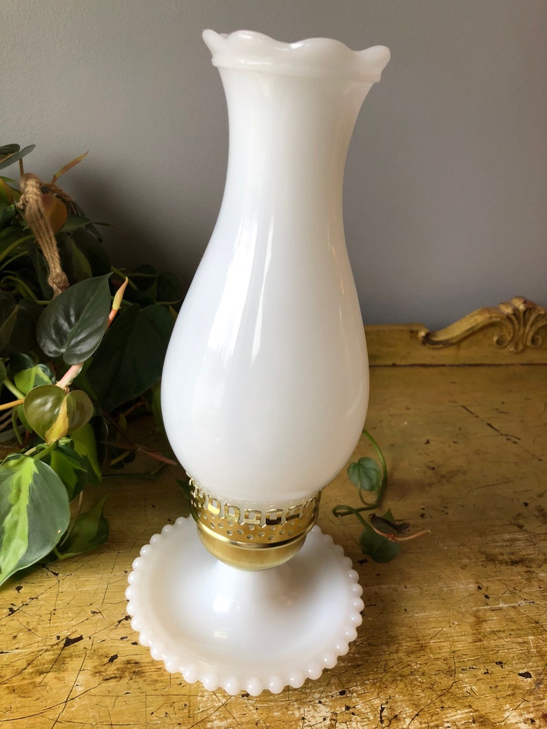 May include: White milk glass lamp with a gold metal base and a scalloped top. The lamp has a beaded base.