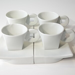 Puede incluir: Juego de cuatro tazas de espresso de cerámica blanca con platillos a juego. Cada taza tiene un asa cuadrada única.