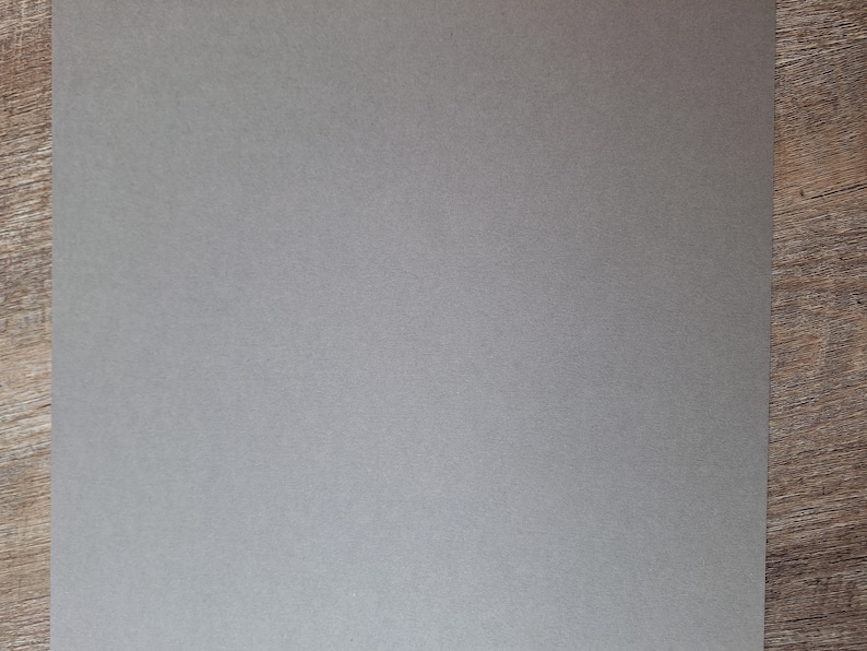 K&ouml;nnte beinhalten: Ein Blatt graues Kartonpapier mit einer dezenten strukturierten Oberfl&auml;che.