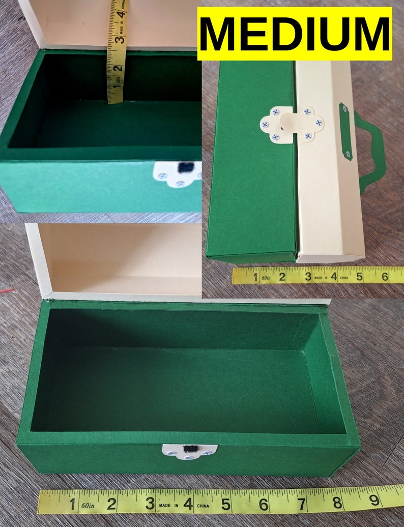 K&ouml;nnte beinhalten: Eine gr&uuml;ne und cremefarbene Schachtel aus Pappe mit einem Scharnierdeckel und einem Verschluss. Die Schachtel ist mit "MEDIUM" beschriftet. Die Schachtel ist 20 cm lang und 10 cm breit.