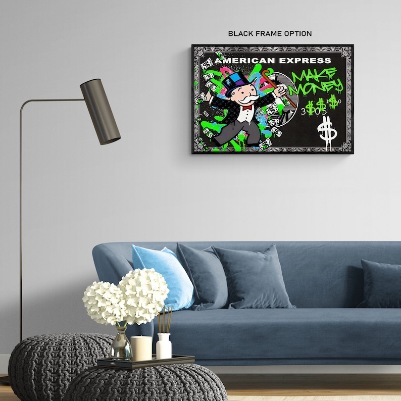 May include: A framed artwork featuring a Monopoly-inspired character with the text "AMERICAN EXPRESS MAKE MONEY." The artwork has a black frame and a black background with green and pink graffiti-style accents. The character is depicted in a suit and top hat.