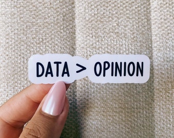 Op de afbeelding: Witte sticker met zwarte tekst die "DATA > OPINION" zegt.