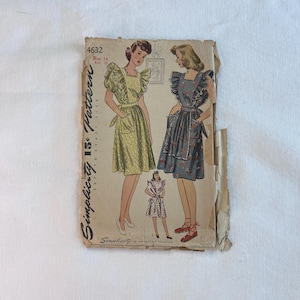 May include: A vintage Simplicity sewing pattern envelope, number 4632, size 14, bust 32. The tan paper cover features illustrations of three figures wearing dresses with ruffled sleeves and aprons, with text including Simplicity 15 cents.