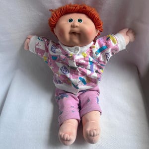 Boneca Cabbage Patch Kids vintage da Hasbro, CPK nº 18, cabelo ruivo, olhos verdes e uma covinha.