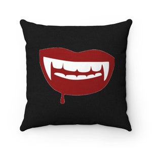 May include: A black throw pillow featuring a red vampire mouth graphic. The mouth is open with white fangs and dripping red blood.