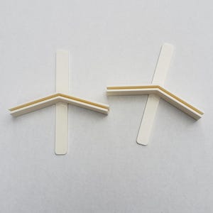 May include: Two white plastic corner braces with a yellow adhesive strip. The braces are designed to reinforce corners and prevent damage.