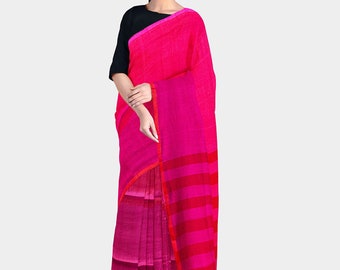 May include: A woman wearing a pink and magenta striped saree with a black blouse. The saree has a gradient effect, fading from a darker pink to a lighter pink.