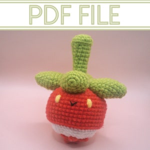 May include: A crocheted plush toy shaped like a red and green radish with a white base. The toy has a small, yellow face with two black eyes and a small, black mouth.