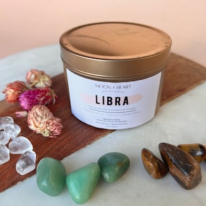 May include: Gold candle tin with a white label that reads "Moon + Heart Burn with Intention Libra Self-Sufficient & Attractive to Many Pumpkin Spice | Vanilla | Sandalwood 100% Soy Candle Handcrafted in Los Angeles 8 oz (226 g)"