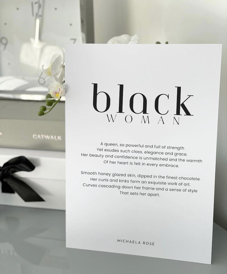 May include: Black and white print with the text "black woman" and a poem about a powerful woman. The poem reads: "A queen, so powerful and full of strength Yet exudes such class, elegance and grace. Her beauty and confidence is unmatched and the warmth Of her heart is felt in every embrace. Smooth honey glazed skin, dipped in the finest chocolate. Her curls and kinks form an exquisite work of art. Curves cascading down her frame and a sense of style That sets her apart." The print is signed "Michaela Rose".