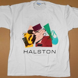May include: White t-shirt with a colourful abstract design featuring shoes and geometric shapes. The text "HALSTON" is printed in black below the design.