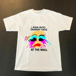 Könnte beinhalten: Weißes T-Shirt mit einem bunten Grafikdesign eines Gesichts mit dem Text "I ran into Tammy Faye at the mall".