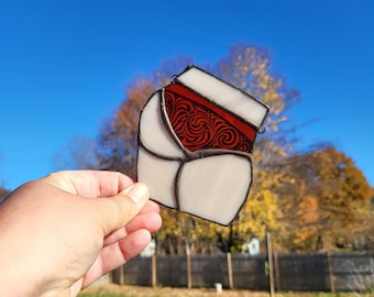 May include: A stained glass window hanging features a white background with a red and white design. The design is a stylized floral pattern.