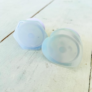 May include: Two clear plastic phone grips, one shaped like a heart and the other a hexagon. Both have a translucent blue color.