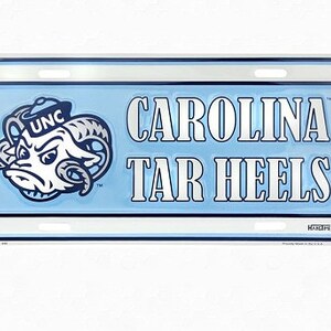 May include: A blue and white metal license plate with the words "CAROLINA TAR HEELS" and a cartoon ram mascot wearing a hat with the letters "UNC" on it.