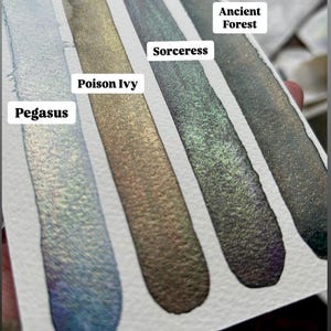 May include: Four swatches of shimmery ink in shades of blue, green, gold, and black. The ink names are Pegasus, Poison Ivy, Sorceress, and Ancient Forest.