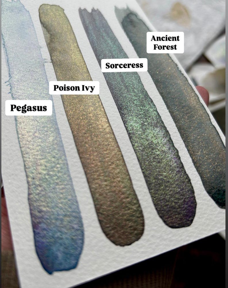 May include: Four swatches of shimmery ink in shades of blue, green, gold, and black. The ink names are Pegasus, Poison Ivy, Sorceress, and Ancient Forest.