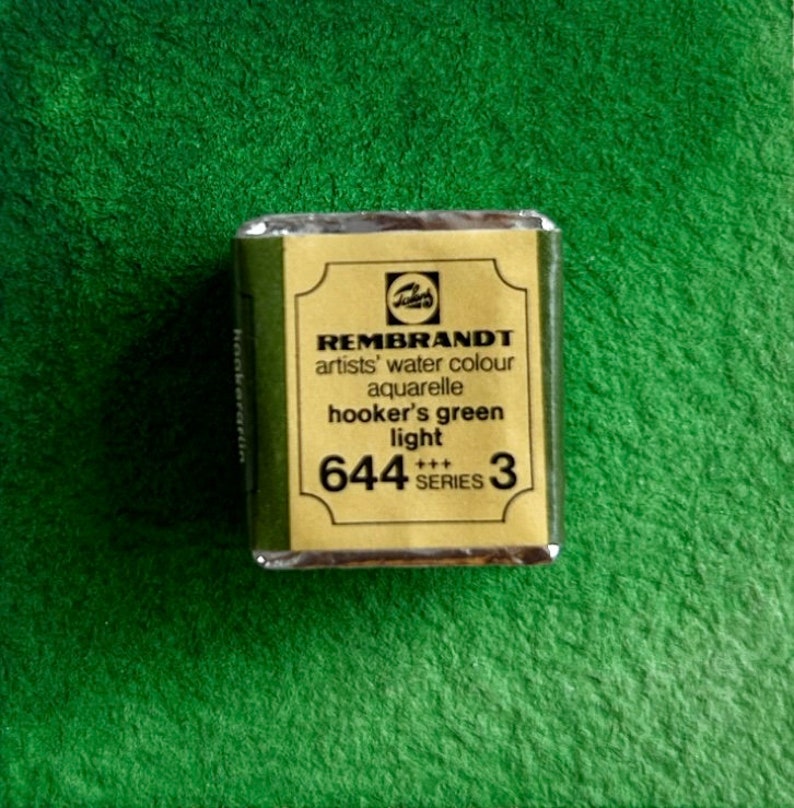 May include: A gold and black watercolor paint tube labeled "REMBRANDT artists' water colour aquarelle hooker's green light 644 +++ SERIES 3"