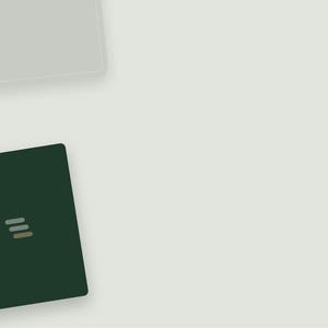 May include: A dark forest green rectangular notebook featuring a small, centred logo composed of three horizontal, stacked bars in light grey, white, and tan colours. The notebook is positioned in the lower left corner of the frame.