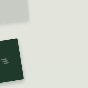 Op de afbeelding: Een donker bosgroen rechthoekig notitieboek met een minimalistisch logo bestaande uit drie horizontale, lichtgrijze, afgeronde balken in het midden van de voorkant. Het notitieboek bevindt zich in de linkerbenedenhoek van het beeld.