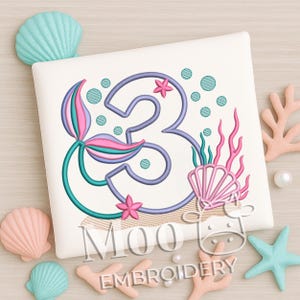 May include: A white square with a teal, pink, and purple mermaid-themed number 3 embroidery design. The design includes a mermaid tail, seashells, coral, and bubbles. The text "MOO EMBROIDERY" is at the bottom.