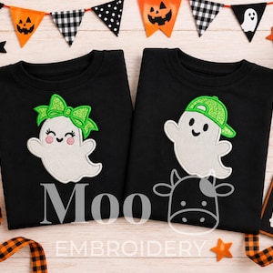 May include: Two black crewneck sweatshirts featuring embroidered ghost designs. The left ghost wears a glittery green bow, and the right ghost wears a glittery green baseball cap. The text Moo EMBROIDERY is printed in white across the bottom.