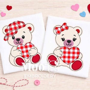 Puede incluir: Dos osos de peluche bordados sobre tela blanca, cada uno sosteniendo un corazón a cuadros rojo y blanco. Uno lleva un sombrero a juego, el otro un lazo. Corazones y botones de fieltro dispersos.