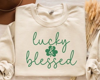 May include: A cream-colored sweatshirt with the text "lucky & blessed" in green lettering with a green four-leaf clover.