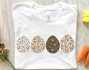 Peut inclure: T-shirt blanc avec un motif de trois œufs de Pâques en imprimé léopard brun et blanc.