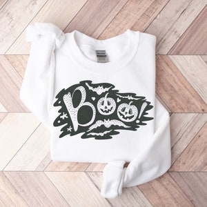 May include: White sweatshirt with a black graphic design of the word "BOO!" with bats and pumpkins.