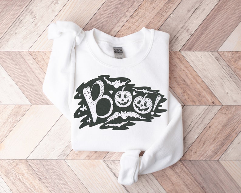 May include: White sweatshirt with a black graphic design of the word "BOO!" with bats and pumpkins.