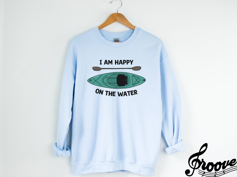 May include: Light blue sweatshirt with a graphic of a kayak and paddles, and the text "I am happy on the water".
