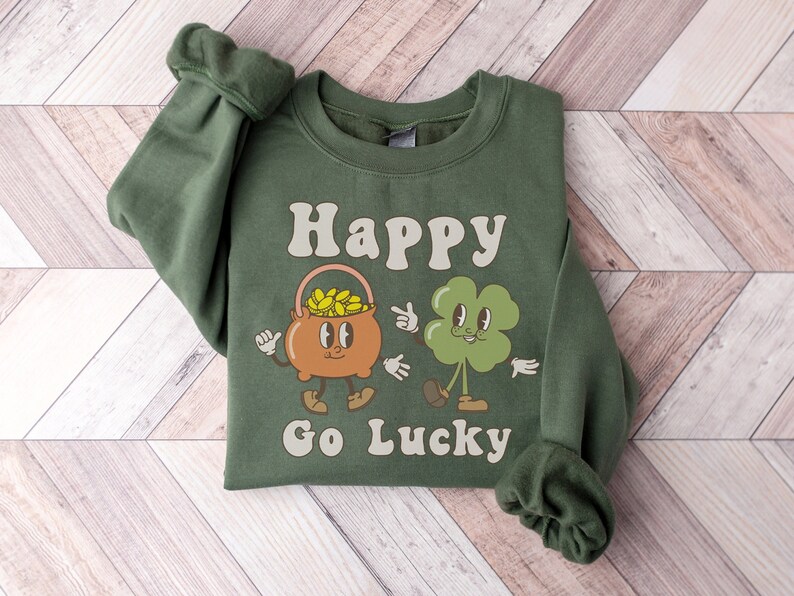 May include: Green sweatshirt with a cartoon pot of gold and a four-leaf clover with the text "Happy Go Lucky"