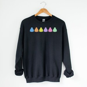 Peut inclure: Sweat-shirt noir avec une rang&eacute;e de cinq Peeps de couleur pastel, une confiserie populaire &agrave; base de guimauve, imprim&eacute;e sur la poitrine.