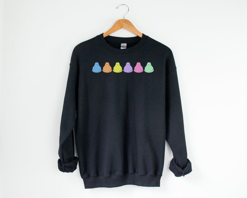 Peut inclure: Sweat-shirt noir avec une rang&eacute;e de cinq Peeps de couleur pastel, une confiserie populaire &agrave; base de guimauve, imprim&eacute;e sur la poitrine.